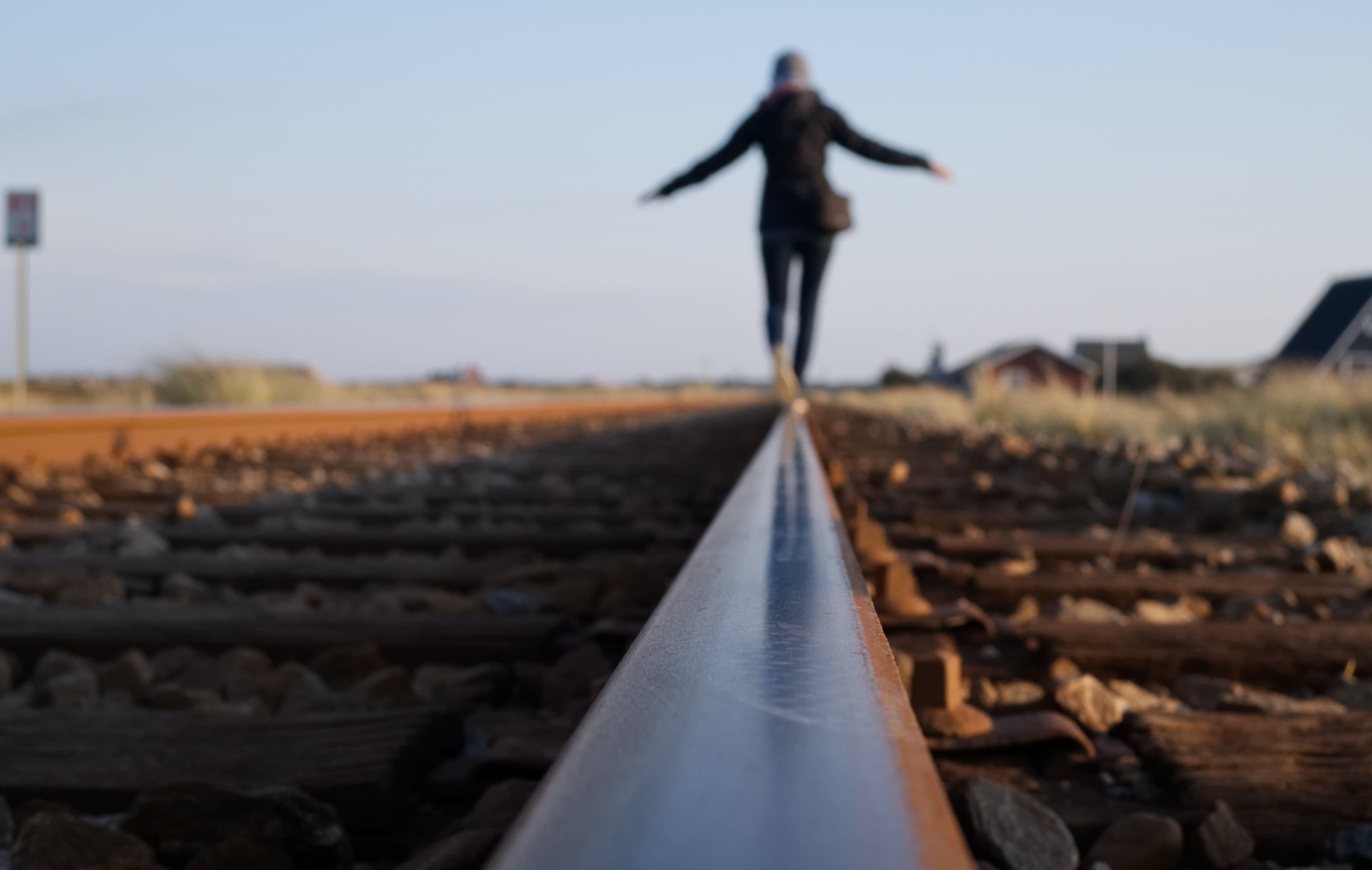 Woman balancing on a train track rail on a clear day